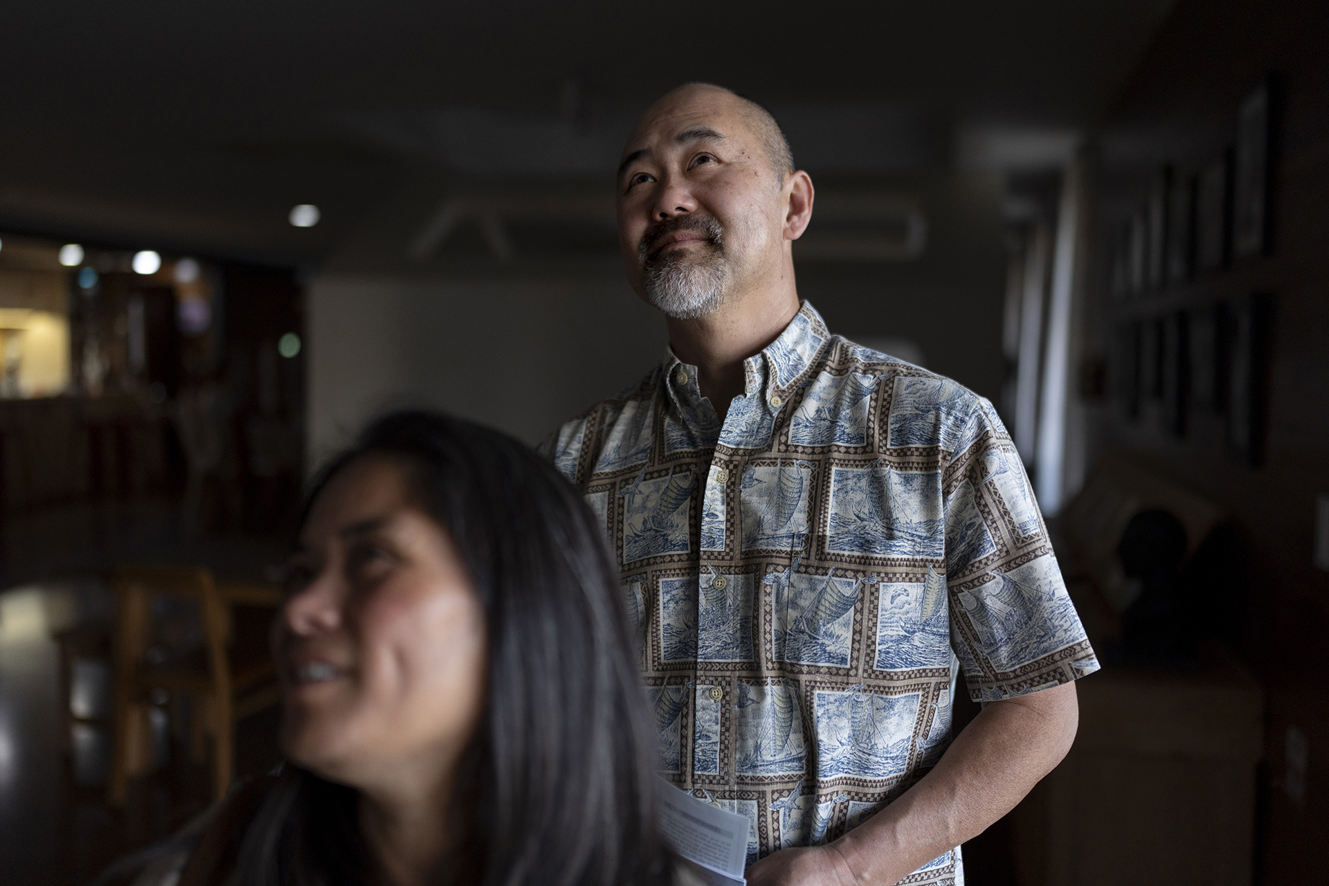 Kenneth Barthel stands behind his wife and looks upwards.