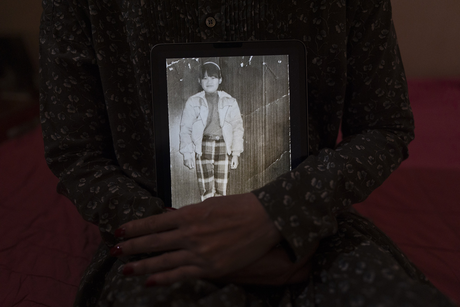 Yooree Kim’s arms are shown holding a tablet displaying a black and white picture of her as a child.